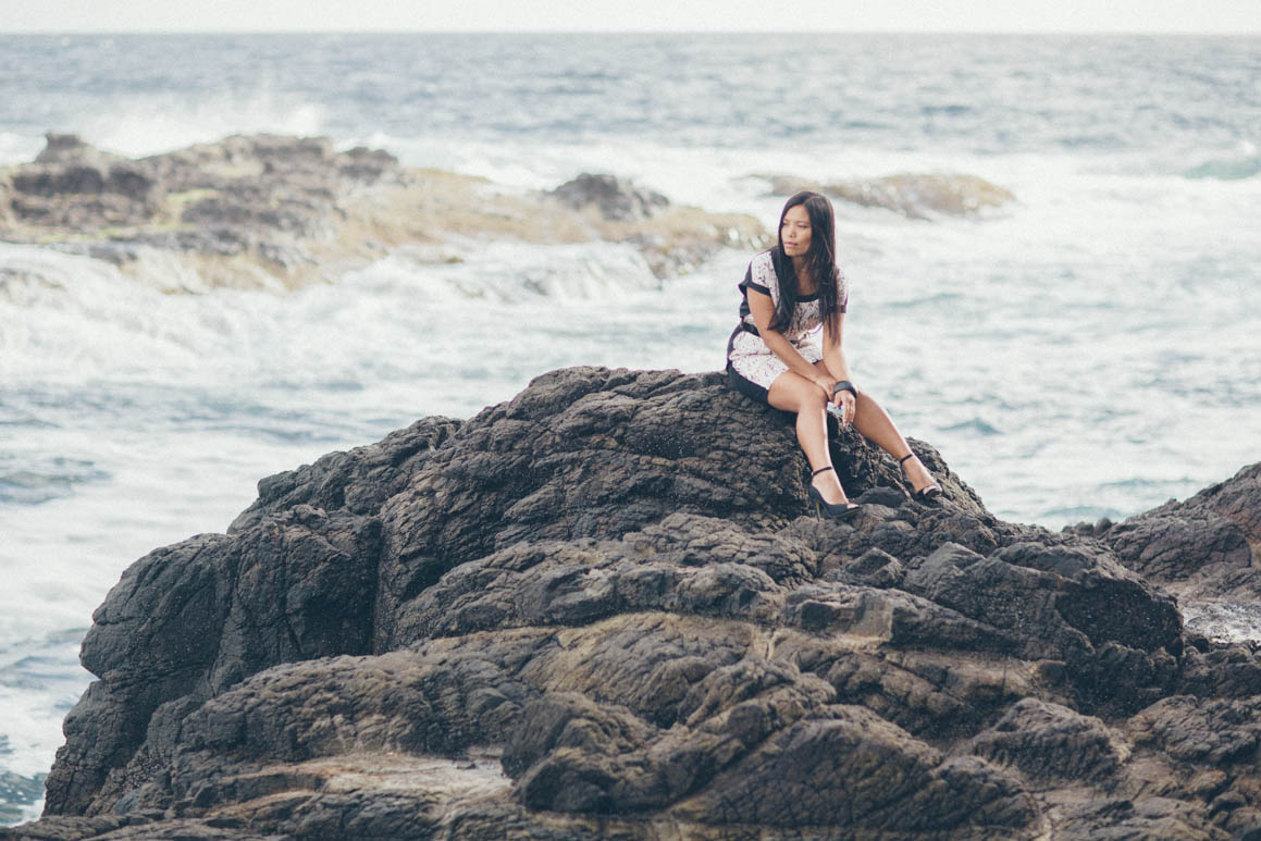 girl sitting on the rocks - waves in the background - ocean