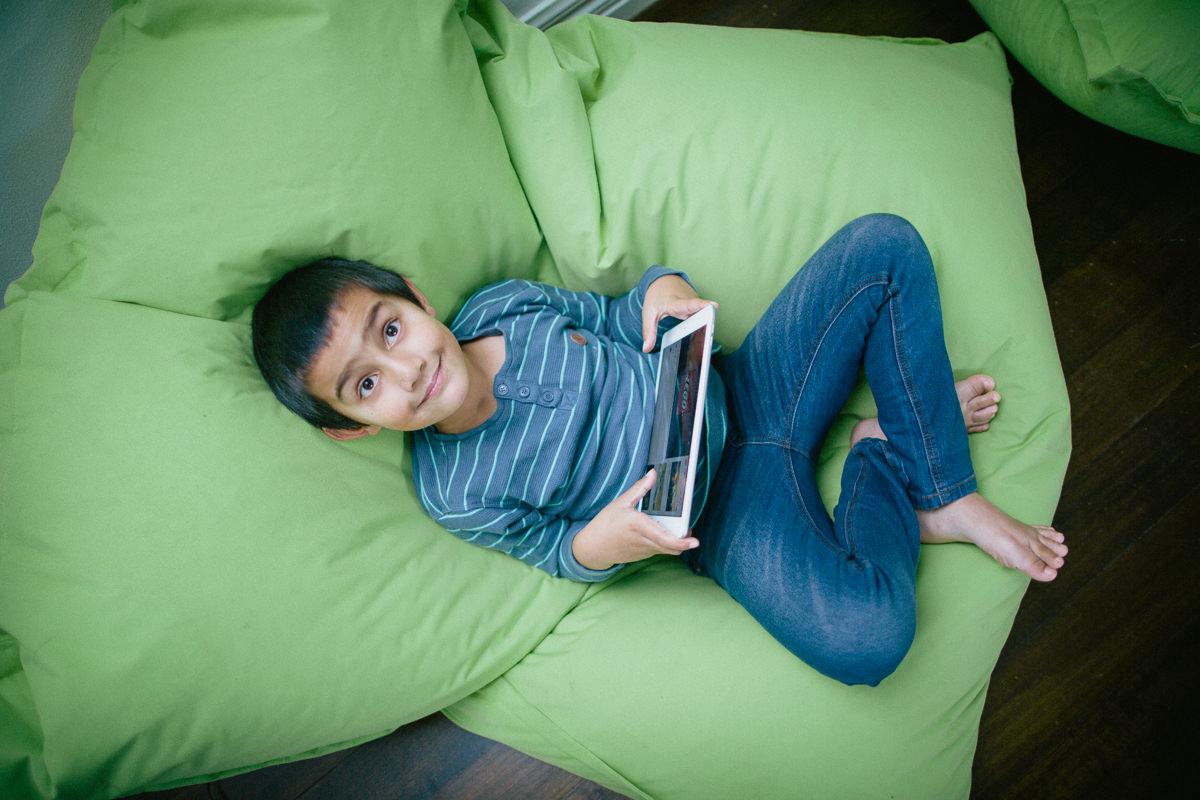 kid using portable internet - ipad - in bean bag - fun lifestyle photography - portable internet
