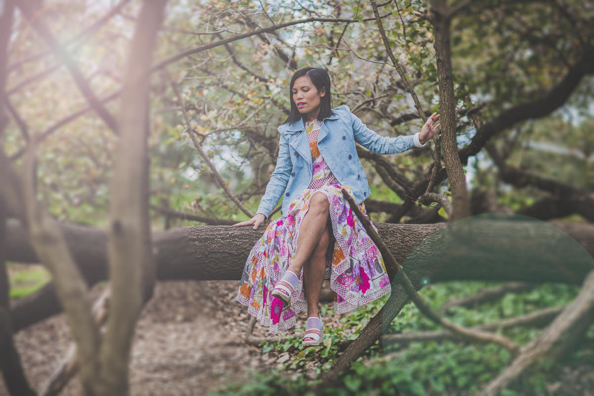 girl sitting on tree in floral skirt