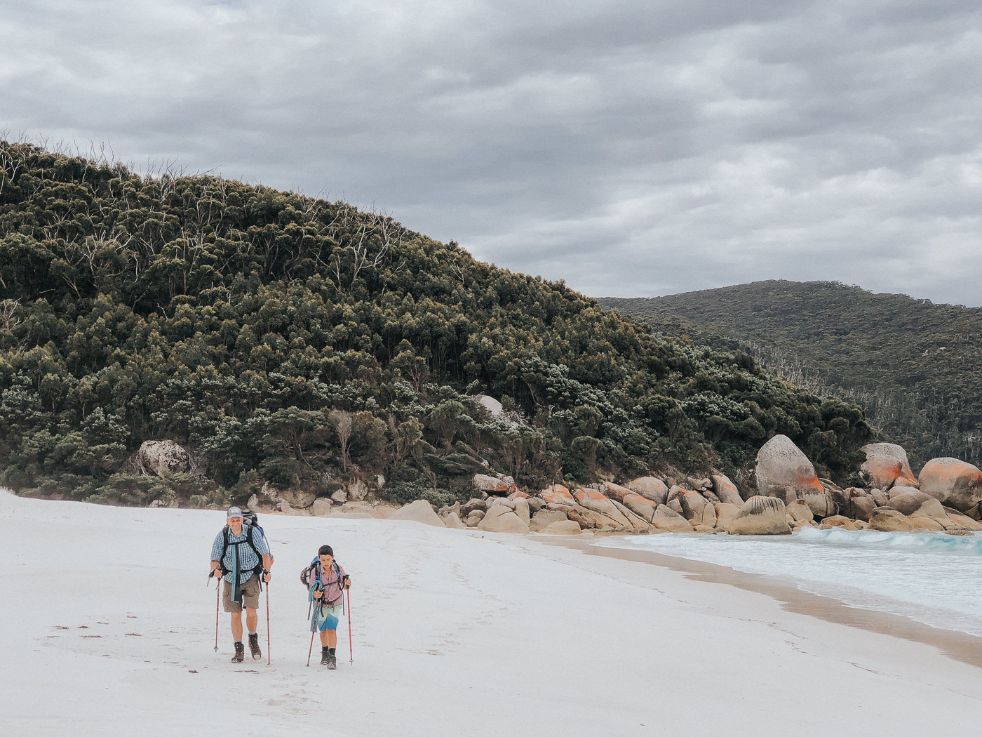 outdoor adventure with kids - father and son hiking along the beach with camping gear