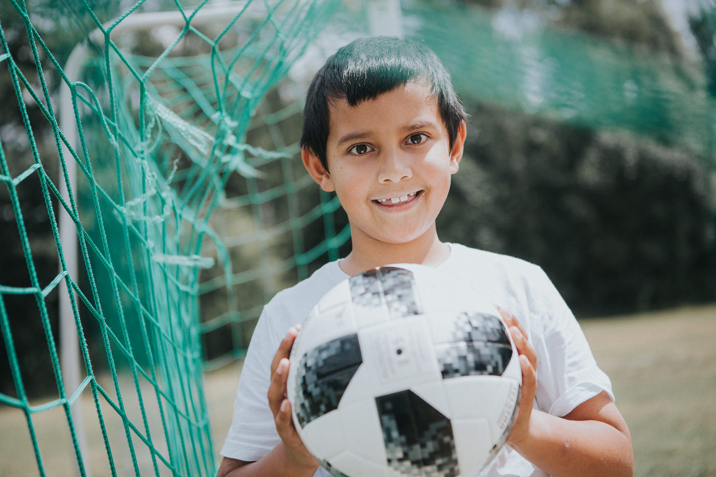 boy holding soccer ball - with net in the background - soccer advertising photo