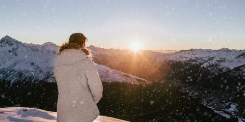 Winter holiday in Europe - Girl looking out in the alps at sunset